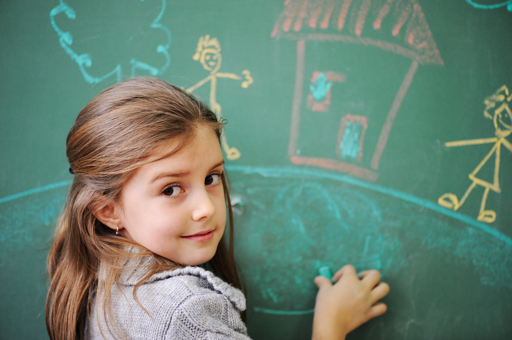 Cute little girl drawing on blackboard